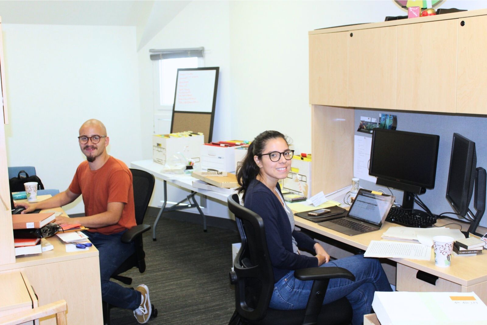 Two graduate students sit in their office as part of the graduate residency program.